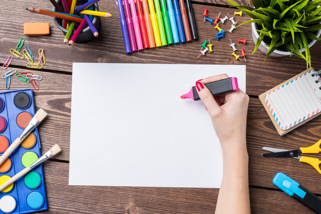 Woman's hand drawing on empty sheet of paper. School or art background